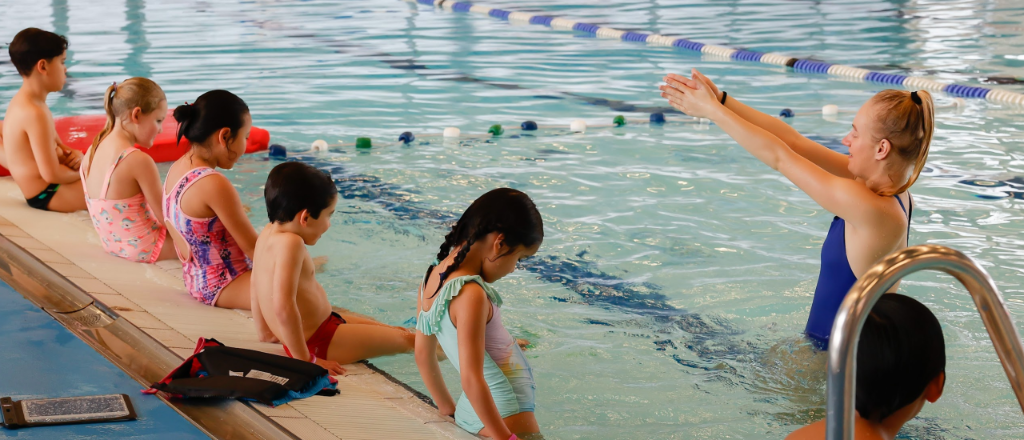 Zwemles instructeur met kinderen bij het bad